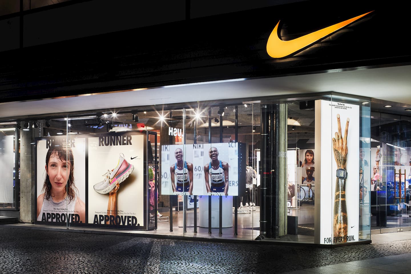BRAINARTIST: Westliche Ansicht des Eingangs des Berliner Nike-Stores mit Kampagnen-Motiven im Schaufenster für den React Infinity Run Flyknits